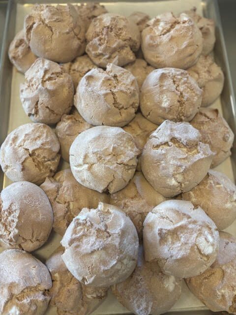 A tray of traditional cracked Mexican cookies dusted with powdered sugar.
